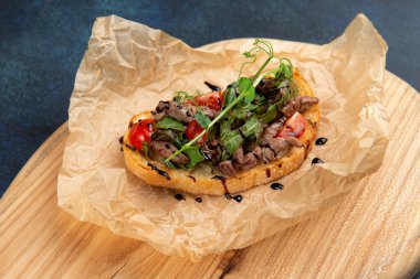 Etli, domatesli ve şifalı otlar. Karanlık bir arka plana karşı. Seçici odak.