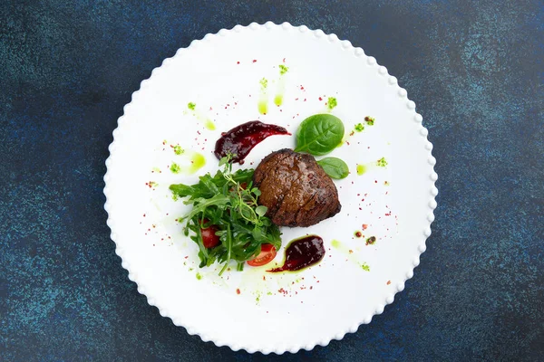 Roka ve domatesli biftek madalyonları. Karanlık bir arka plana karşı. Seçici odak.