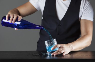 Bir içki gri bir arka plan üzerine dökülen barmen