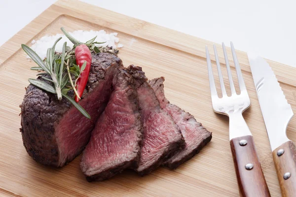 Bistecca con spezie su un pannello di legno, vicino alla forchetta e al coltello — Foto Stock