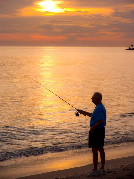 A man fishing at sea shore in the evening