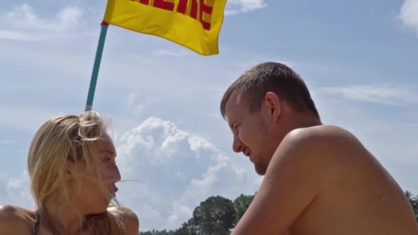 Ein Paar versöhnt und küsst sich. Strand auf einem Hintergrund aus Wolken und einer Flagge — Stockvideo