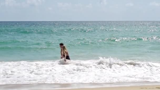 Pasangan kekasih di pantai berpegangan tangan dan masuk ke dalam air — Stok Video