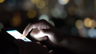 Sosyal Net çatı büyük şehirde akşam zaman cep telefonu kullanarak tarama adam. Yakın çekim. 4k