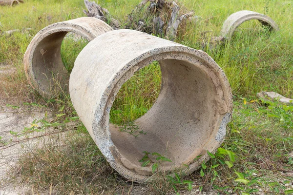 Old broken concrete cement pipe in grass,  Old concrete pipes, Cracked and deteriorated sewer pipes are left or placed on the ground.