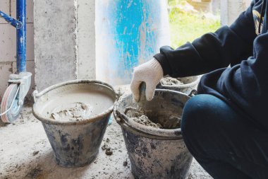  İnşaatta çimento taşımak için plastik kovalar plastik kovada çimento karıştırmak için işçiler havan toplarını karıştırıyor.. 