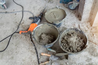 İşçi havanı karıştırır. Islak Beton ya da motrar karışımı. Gri harç, beton yüzey. Çözüm karıştırıldı, apartman yenilendi..