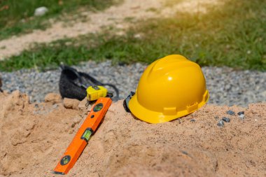 İnşaat alanındaki kumda sarı kask, inşaat projesinin inşaatı için sağlam şapka planı..