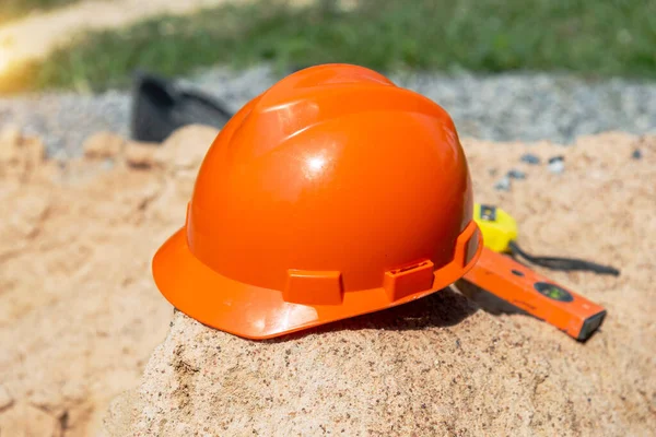 Orange  helmet on sand in construction site, Hard hat blueprint building construction estate project development.