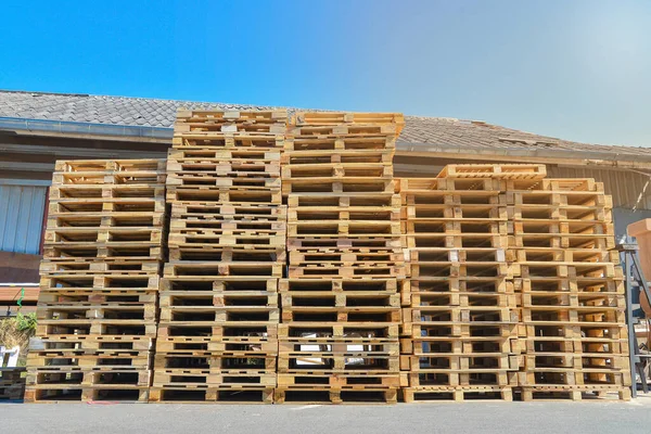 A stack of pallets sit outside a building, Wooden pallet.
