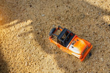 Çocukların plastik oyuncakları yeşil uçlu sarı araba, kürek, kırmızı kova, kumsalda sarı kumlu yeşil top