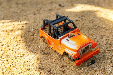 Çocukların plastik oyuncakları yeşil uçlu sarı araba, kürek, kırmızı kova, kumsalda sarı kumlu yeşil top