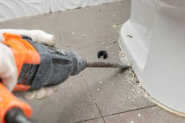 İşçi tuvaletteki boruyu tamir etmek için klozetin tamiri yapıyor.