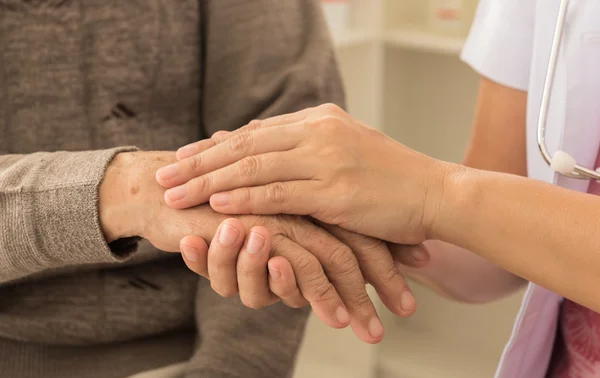 Утешительные руки, доктор держит старшего пациента — стоковое фото