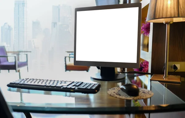 Blank desktop computer with keyboards and other accessories on the desk in a warm light room with clipping path on screen. mock up
