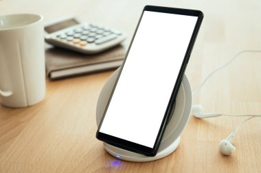 Mobil akıllı telefon kablosuz hızlı şarj cihazına yerleştirilir. Reklamınız için kırpma yolu olan boş ekran.