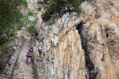 Bir kadın, Cantabria 'daki Faro del Caballo deniz fenerine doğru merdivenlerden çıkıyor. Doğada yürümek