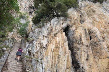 Bir kadın, Cantabria 'daki Faro del Caballo deniz fenerine doğru merdivenlerden çıkıyor. Doğada yürümek
