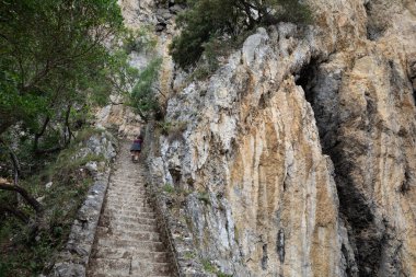 Bir kadın, Cantabria 'daki Faro del Caballo deniz fenerine doğru merdivenlerden çıkıyor. Doğada yürümek