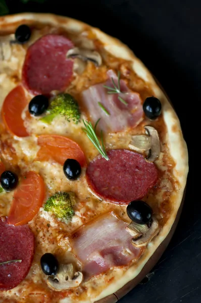 Pizza with salami, bacon, broccoli, olives on dard background. — Stock Photo, Image