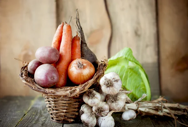 Raw vegetables in a basket on a wooden table. — Stock Photo, Image