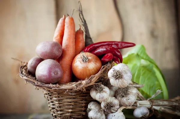 Légumes crus dans un panier sur une table en bois . — Photo