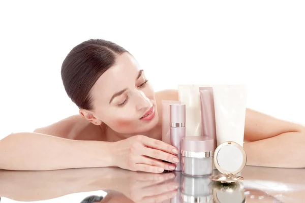 Ung kvinna med en välskött hud nära krämer kosmetika. — Stockfoto