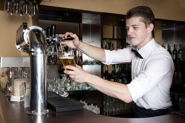 Barman derrama cerveja em um copo — Fotografia de Stock