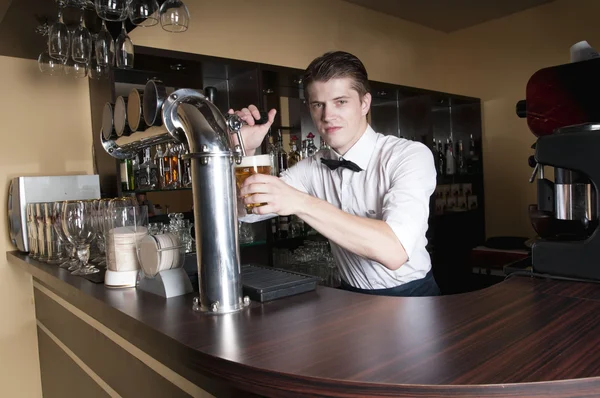 Barman pours beer into a glass — Stock Photo, Image