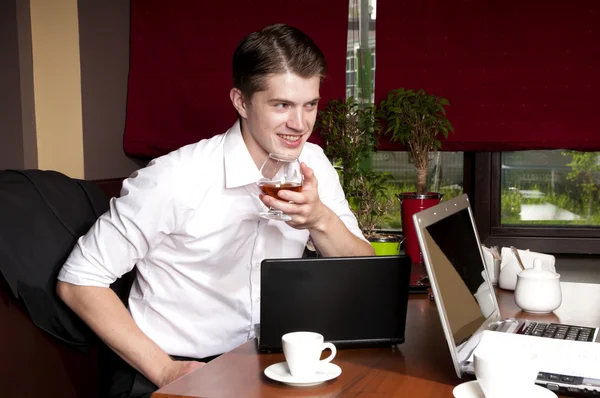 Uomo che beve alcol quando lavora con un computer portatile — Foto Stock