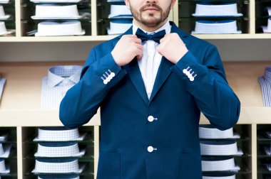 Handsome young man in classic suit against showcase with shirts clipart