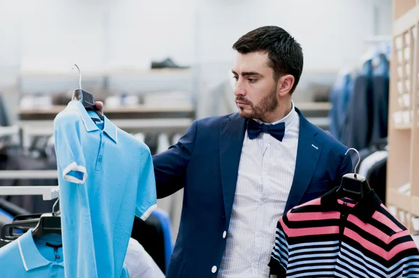 Atractivo joven elige camiseta - camisa en una tienda . — Foto de Stock