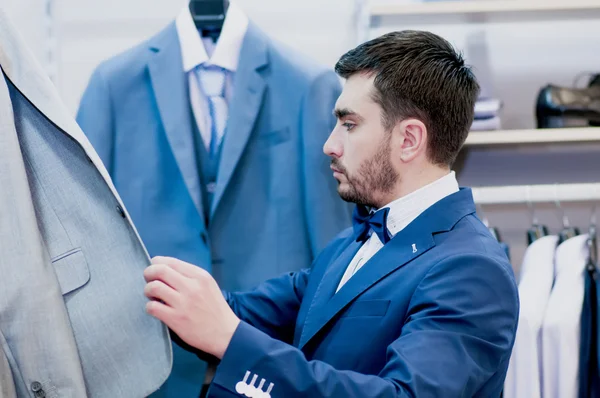 Hombre guapo elige una chaqueta de traje — Foto de Stock