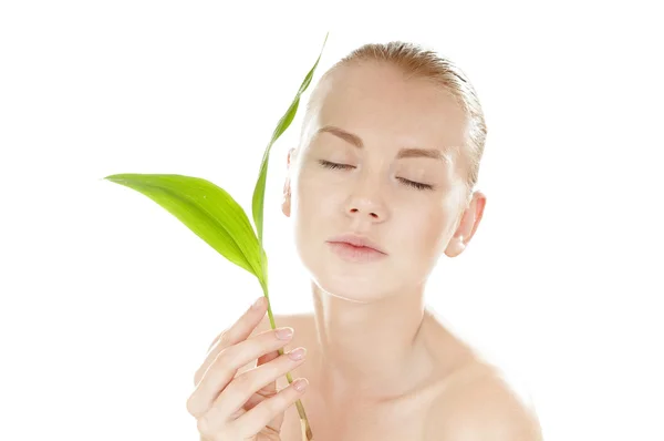 Woman with a healthy and well-groomed complexion holding green leaf in front of her face. — Stock Photo, Image