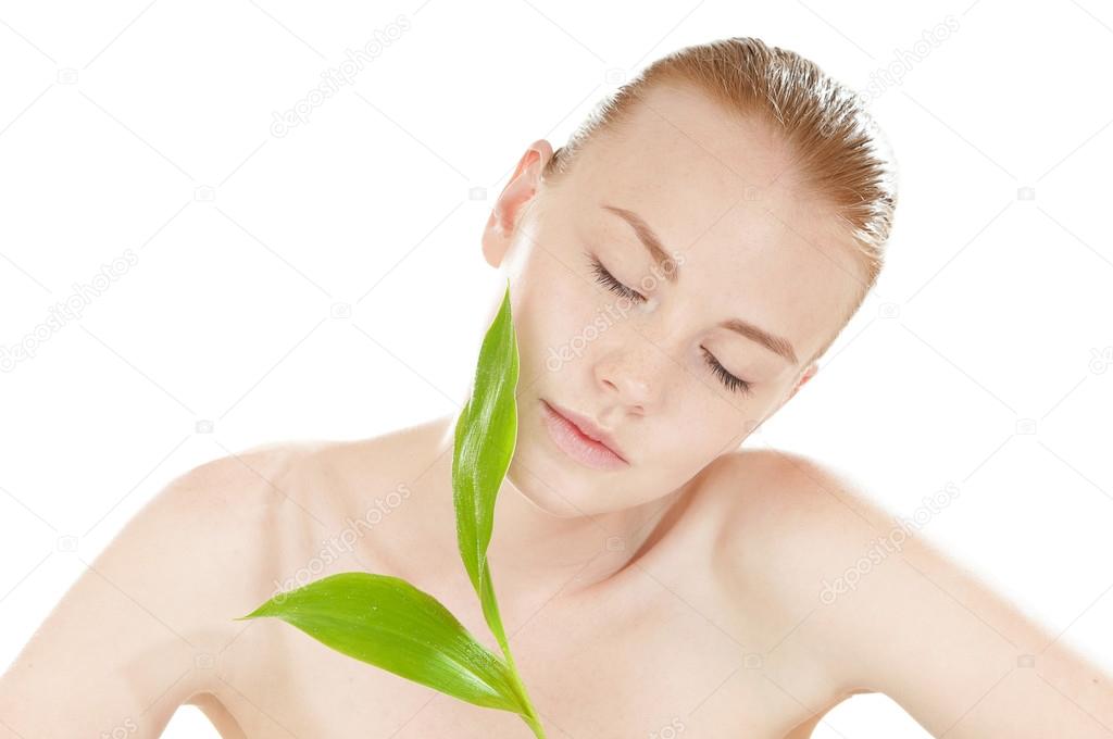 Woman with a healthy and well-groomed complexion holding green leaf in front of her face