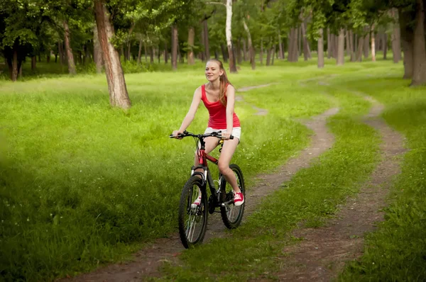 Gadis cantik bersepeda di jalan hutan — Stok Foto