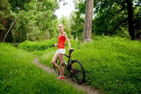 Gadis cantik bersepeda di jalan hutan — Stok Foto