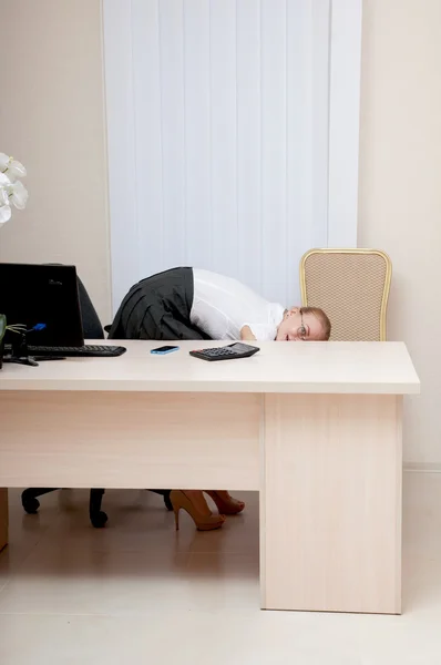 Cute young business woman hiding behind a desk. — Stock Photo, Image