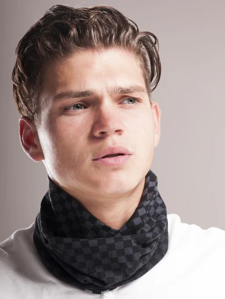 Beau jeune homme avec une coiffure bouclée portant une écharpe — Photo