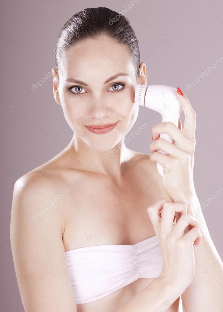 Charming woman with brush for deep cleansing facial