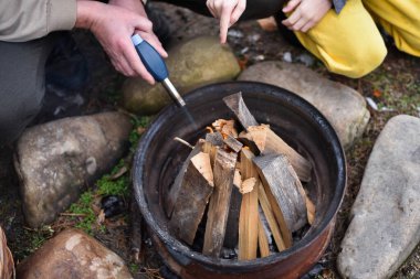 Baba oğul arka bahçede gaz tabancasıyla ateş yakıyor, kışlık giysiler içinde.