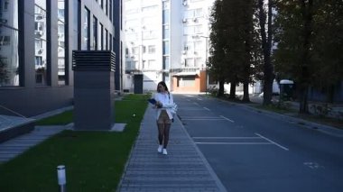 İş kadını işe giderken modern binanın önünden geçen belgelere göz atıyor.