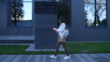 İş kadını işe giderken modern binanın önünden geçen belgelere göz atıyor.