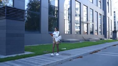 İş kadını işe giderken modern binanın önünden geçen belgelere göz atıyor.