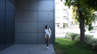 Modern bir şehir binasının terasında elinde defteriyle bir iş kadını.