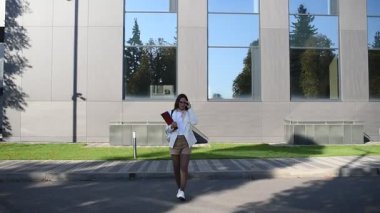 İş kadını işe giderken modern binanın önünden geçen belgelere göz atıyor.