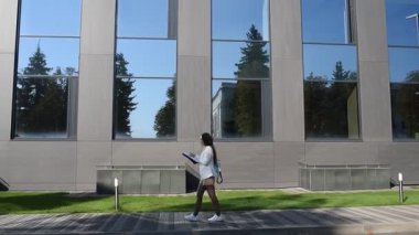 İş kadını işe giderken modern binanın önünden geçen belgelere göz atıyor.