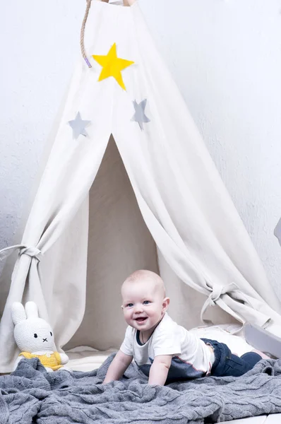 Carino bambino striscia sul tappeto grigio lavorato a maglia vicino wigwam . — Foto Stock