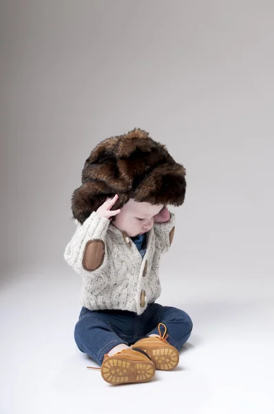 有趣的男婴，冬季皮毛帽子盖灰色背景. — 图库照片