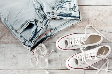 Kulaklık, kot pantolon, lastikbotlar yalan ahşap kurullarında.